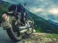 Motocykl gotowy na przygodę, z bagażem na siedzeniu, na tle gór i mapy świata. Marzy o podróży na Atlantic Road w Norwegii.