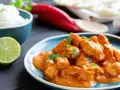 Un saporito spezzatino di pollo in salsa cremosa, guarnito con prezzemolo fresco, accompagnato da riso bianco, lime e peperoncino rosso.