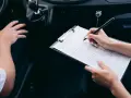 Kobieta wypełnia formularz rejestracji auta, siedząc obok kierowcy.