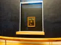 Mona Lisa w muzeum, za pancerną szybą. Słynny obraz Leonarda da Vinci przyciąga tłumy zwiedzających.