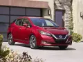 Czerwony Nissan Leaf przed nowoczesnym domem. Sprawdź atrakcyjną nissan leaf cena i wybierz swój wymarzony samochód elektryczny.