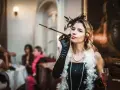 Kobieta w stylu lat 20. z cygaretką i piórami, na tle imprezy.