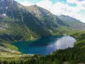 Największe jezioro w Tatrach, Morskie Oko, otoczone zielonymi lasami i skalistymi szczytami.