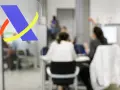 Logo de Hacienda en primer plano. Al fondo, personas atendiendo trámites, quizás esperando cuando devuelve Hacienda.
