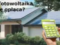 Dom z panelami fotowoltaicznymi na dachu. Obok kalkulator, sugerujący opłacalność inwestycji w fotowoltaikę w domu.