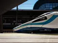 Nowoczesny pociąg PKP Intercity z niebieskimi pasami na tle dworca.