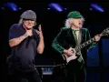 Brian Johnson i Angus Young, legendarny skład AC/DC, na scenie. Brian śpiewa do mikrofonu, Angus gra na gitarze.