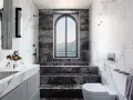 Bagno di lusso con vasca doccia in muratura, rivestimenti in marmo e vista panoramica.