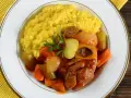 Risotto giallo e ossobuco con verdure, un classico dei piatti tipici milanesi, guarnito con prezzemolo e scorza di limone.