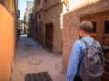 Młoda osoba z plecakiem idzie wąską uliczką w Marrakeszu. Czy w Marrakeszu jest bezpiecznie? Tak, zwiedzanie jest przyjemne.