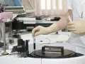 Pracownik w rękawiczkach umieszcza próbkę w automacie analitycznym w laboratoriach Brunel B Co.