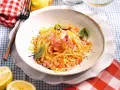 Spaghetti con sughi in bianco, conditi con limone, mandorle e un tocco di rosa.