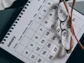 Okulary leżą na kalendarzu z datami po angielsku, pokazującym styczeń.