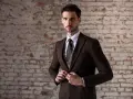 Elegancki mężczyzna w brązowym garniturze, idealny na stylizacje na wesele zimą.