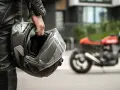Motociclista con casco, simbolo di sicurezza e certificazione casco moto. Moto rossa sfocata sullo sfondo.