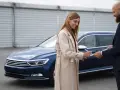 Kobieta podpisuje dokumenty, co może oznaczać uzyskanie kredytu na samochód używany. Obok stoi mężczyzna w garniturze.