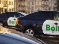 Ciemne samochody z logo Bolt, gotowe do pracy taxi bez licencji, stoją na ulicy.