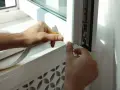 Mani applicano nastro isolante per sigillare le finestre dagli spifferi, migliorando l'isolamento termico.