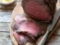 Roast beef ricetta classica: succulento arrosto affettato su tagliere di legno, pronto per essere gustato.