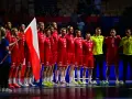 Drużyna piłkarzy ręcznych w czerwonych strojach z polską flagą. To ważny moment w 2 lidze piłki ręcznej.