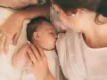 Delikatne karmienie noworodka. Mama czule tuli dziecko, które śpi, ssąc pierś. Wskazówki, jak wybudzić noworodka do karmienia, mogą być pomocne w takich chwilach.