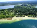 Malownicze warchały jezioro otoczone lasem, z piaszczystą plażą, pomostami i kolorowymi łódkami.