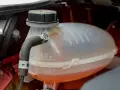 A car's coolant reservoir with MAX and MIN lines. The orange coolant is between the lines, indicating the correct level. This image helps answer "what coolant does my car need.