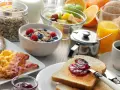Deftiger Brunch in Schleswig-Holstein: Rührei, Speck, Würstchen, Müsli, Obst, Saft und Kaffee.
