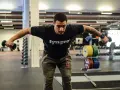 Man tränar baksida axlar med hantlar på gym.