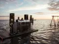 DJ na wodnej platformie podczas Salt Wave Festival. W tle huśtawka na jeziorze o zachodzie słońca.