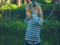 Ein Kind mit Kopfhörern im Freien, das die Welt der Klänge entdeckt. Diese Szene zeigt die Reizoffenheit bei Kindern, die sich neugierig auf neue Erfahrungen einlassen.