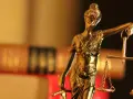 Justitia-Statue mit Waage und Schwert, symbolisiert Gerechtigkeit. Im Hintergrund unscharfe Bücher, die auf einen Fall mit 1/3 Betreuung hindeuten könnten.