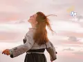 Embracing the sky, a woman with flowing red hair embodies joy, a feeling achievable through 7 daily habits. A butterfly and smiley faces float above.