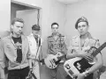 Les membres de The Clash posent avec leurs guitares. L'un porte un t-shirt "The Clash".