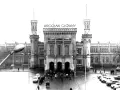 Wrocław Główny, imponujący dworzec z wieżami i zegarem, otoczony samochodami i ludźmi.