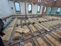 Rozpoczęła się wymiana stropu w starym domu. Metalowe belki i prefabrykowane elementy stropowe czekają na montaż.