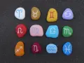 Kolorowe kamienie z symbolami zodiaku, ułożone w rzędach. Idealne do sprawdzania dopasowania znaków zodiaku.