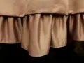 Delikatne marszczenia na **satynowym** materiale tworzą efektowną falbanę, dodając elegancji.