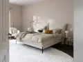 Beige Schlafzimmer Ideen: Einladendes Bett mit beiger Bettwäsche, Akzentkissen und Decke. Weißer Sessel und Teppich schaffen Gemütlichkeit.