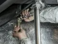 Ręce majstra dokręcają złączkę podczas próby szczelności instalacji c.o. zgodnie z normą.