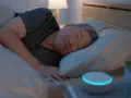 Ein Mann schläft tief und fest, die entspannende white noise wirkung des Geräts neben ihm hilft ihm beim Einschlafen.