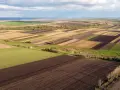 Widok z lotu ptaka na mozaikę pól. Widać odrolnienie i wyłączenie z produkcji rolnej, gdzie niektóre obszary są zaorane, inne zielone, a jeszcze inne przygotowane pod uprawę.