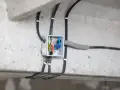 Rozdzielnica modułowa z przewodami elektrycznymi, zamontowana na betonowej konstrukcji.