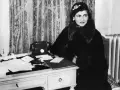 Coco Chanel, icona di stile, al suo scrittoio. La sua storia è fatta di eleganza e innovazione.