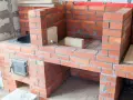Construcción de chimeneas de obra de leña. Ladrillos rojos y mortero gris forman una estructura robusta, lista para encender el fuego.