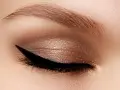 Occhio con trucco cat eyes, eyeliner nero definito e ombretto bronzo scintillante. Sopracciglio curato.