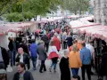 Menschen schlendern über einen belebten kunstmarkt berlin mit vielen Ständen und bunten Markisen.
