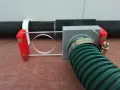 A 3d printed blast gate with a clear sliding mechanism and a green hose attached.