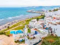 Widok na białe miasteczko z meczetem i turkusowym morzem, w oddali widać port. Tarifa Tanger prom.