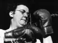 Coluche, lunettes rondes, gants de boxe, prêt à en découdre avec le racisme.